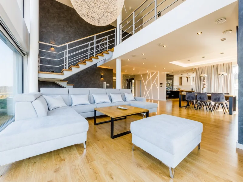 Otwarty salon z antresolą, jasnym narożnikiem i drewnianą podłogą