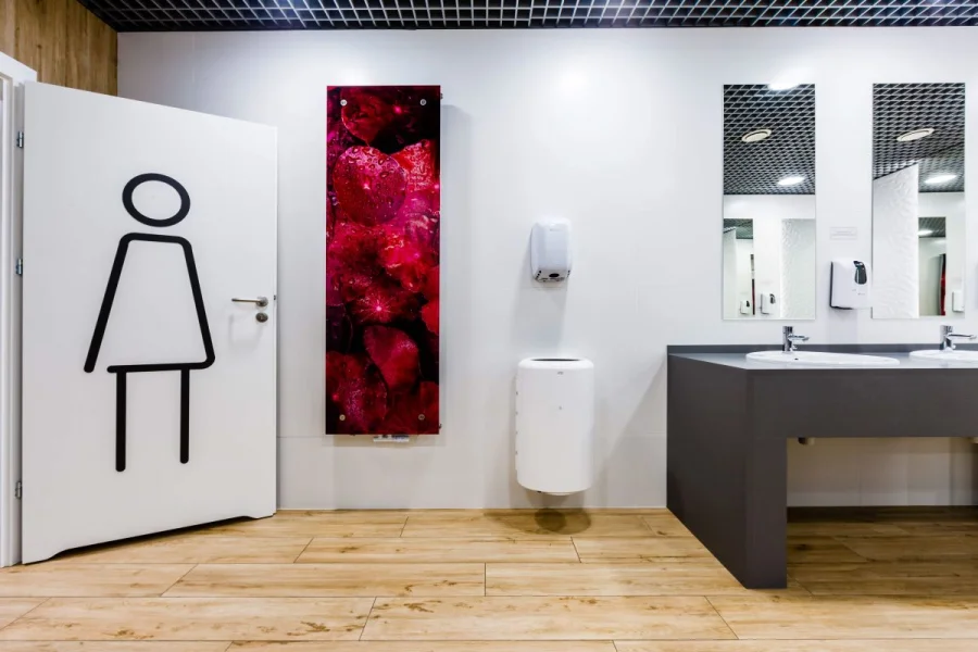 Wejście do toalety damskiej z grafiką na drzwiach i czerwonym obrazem na ścianie