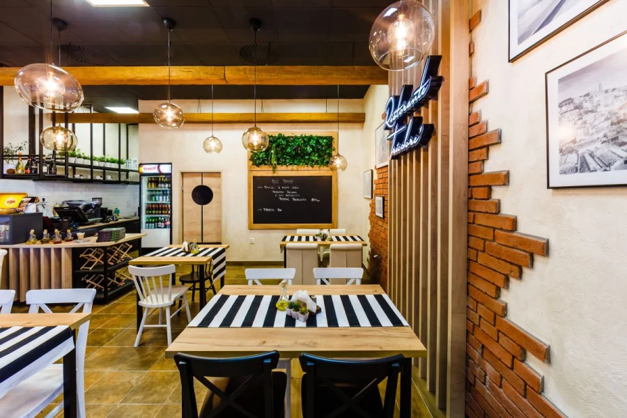 Sala restauracji z czarno-białymi bieżnikami, ceglaną ścianą i fotografiami Włoch