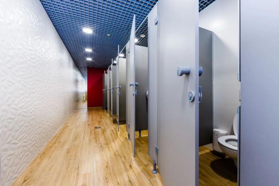 Korytarz z kabinami WC i białą ścianą z płytek 3D