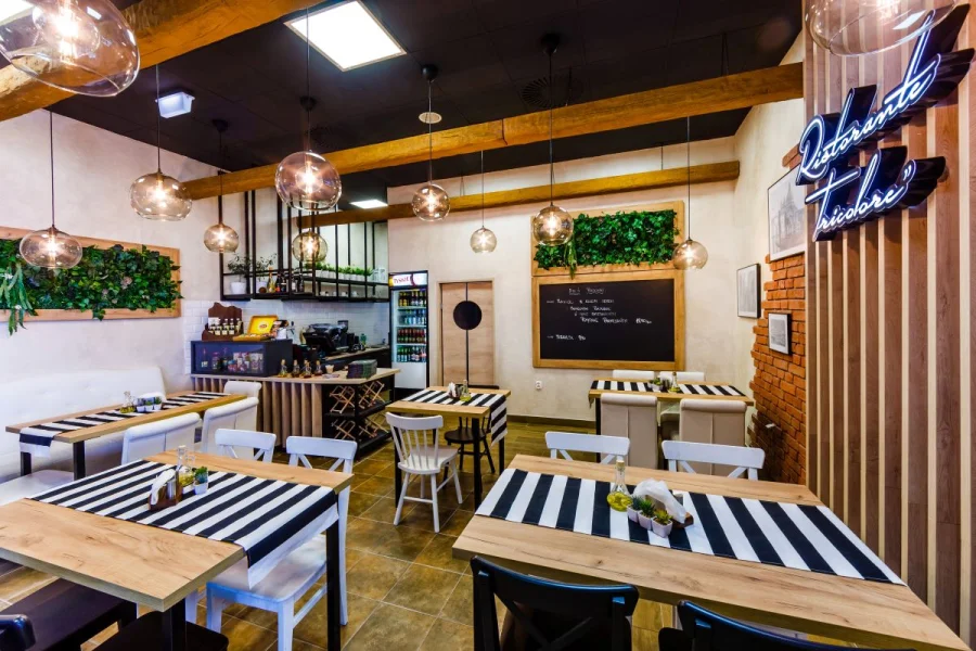 Wnętrze restauracji z tablicami kredowymi, zielonymi panelami z roślin i kulistymi lampami